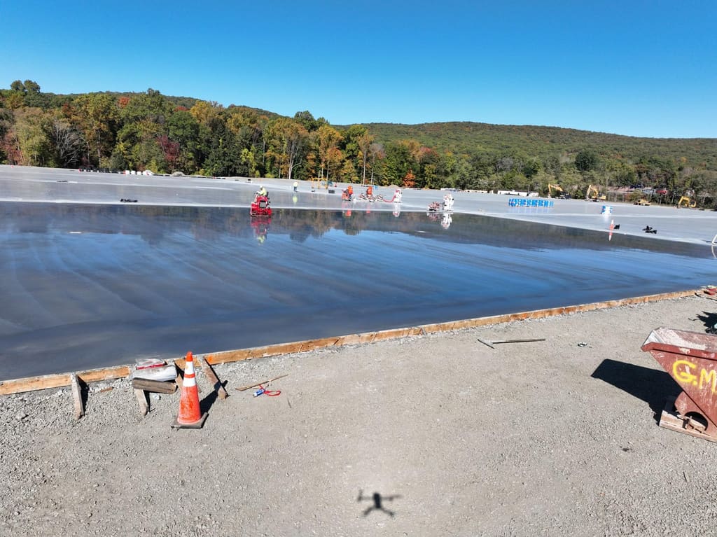 Crew finishing a large freshly poured commercial concrete slab.