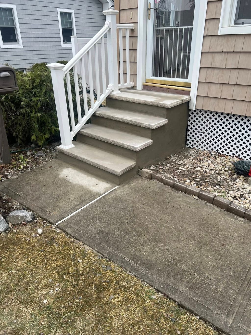 Rebuilt concrete front stoop and steps at a home entry.