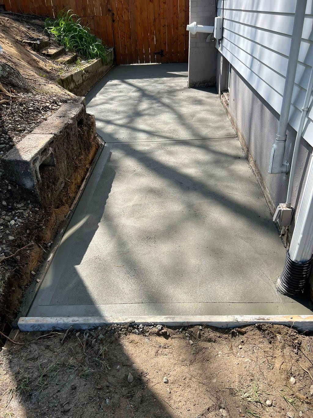 Freshly poured side-yard patio concrete pad.