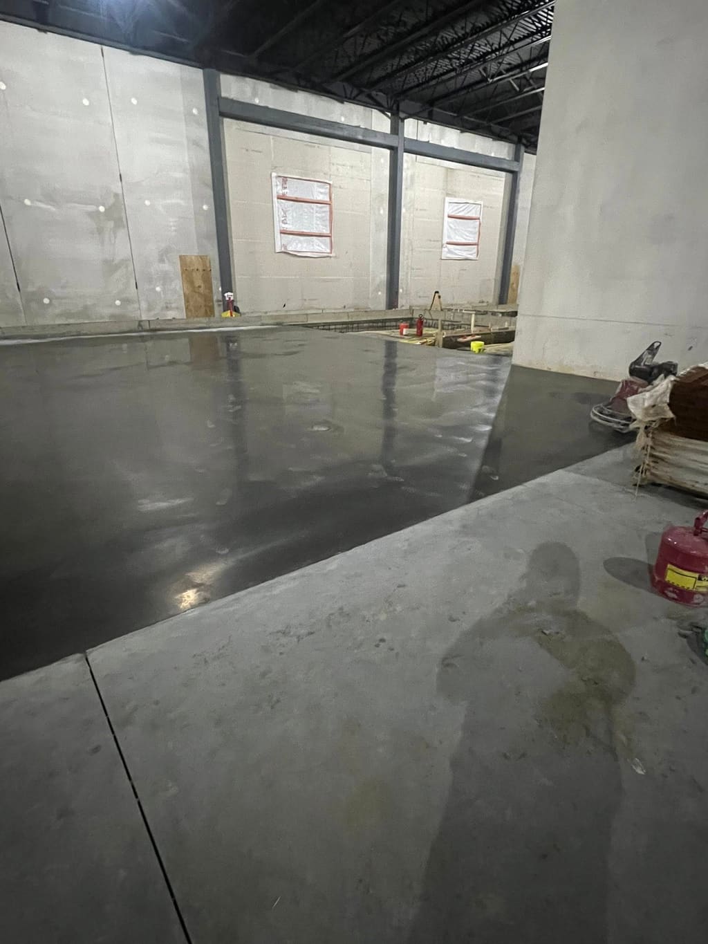 Large freshly troweled interior concrete floor slab inside a commercial building under construction.