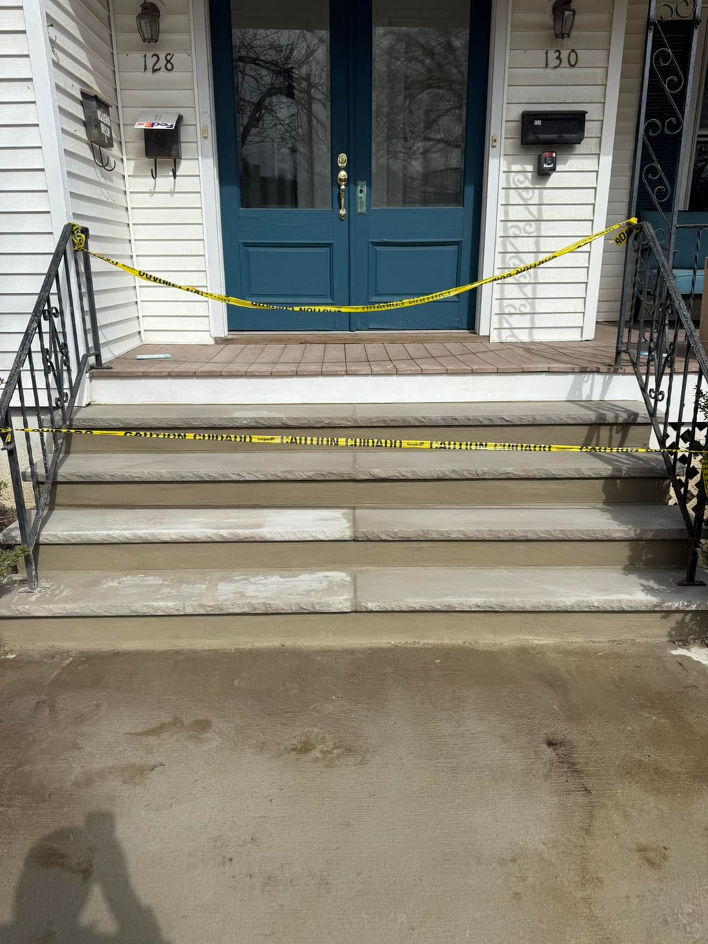 Rebuilt concrete entry steps with a brick-paver landing and new walkway at a home's front door.