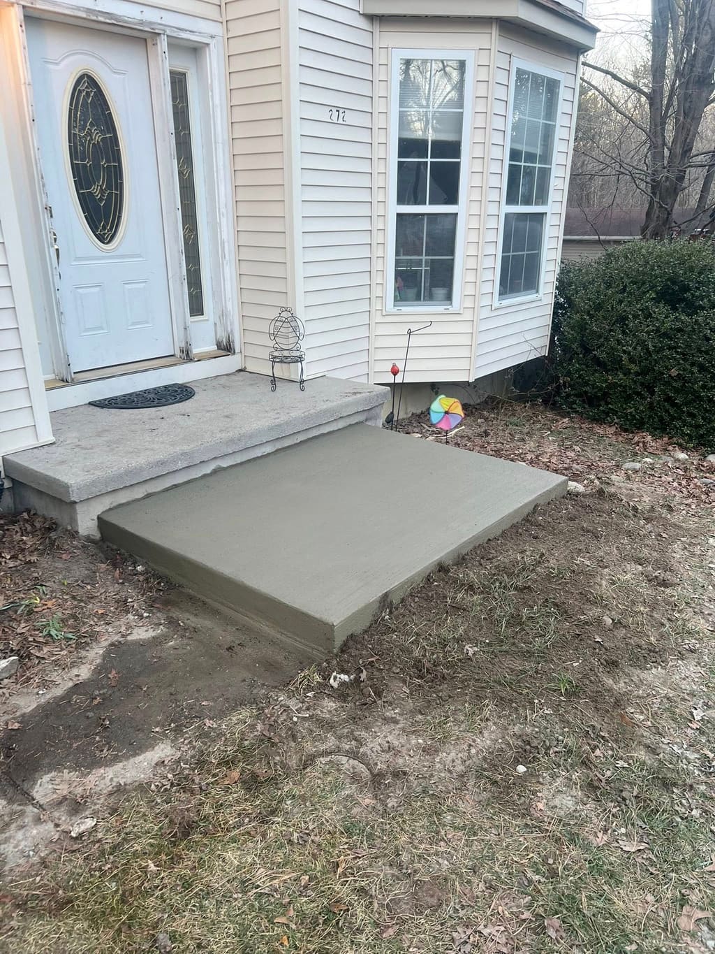 Freshly poured smooth concrete stoop and landing at a home's front entry door.