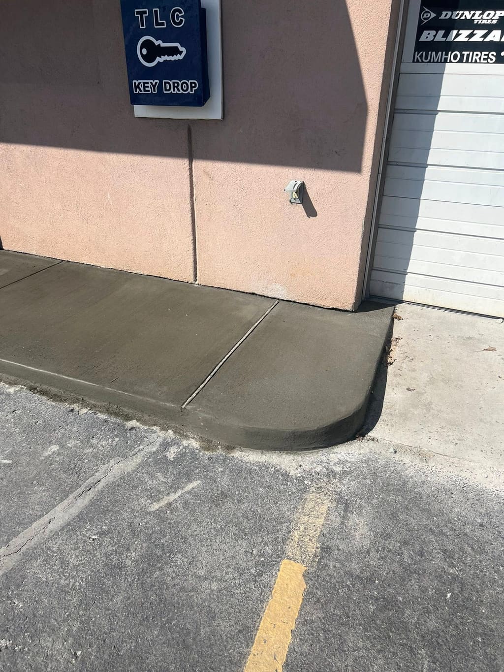 Finished concrete walkway with a curved curb edge meeting the asphalt parking lot at a commercial building.