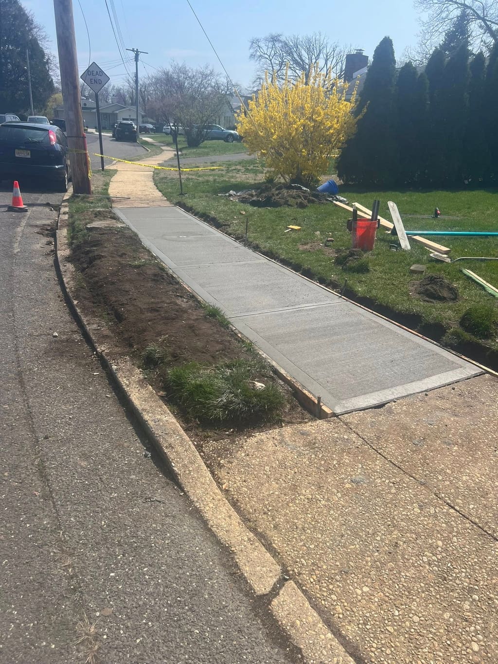 A newly poured concrete sidewalk sits between wood forms at a residential jobsite in progress.