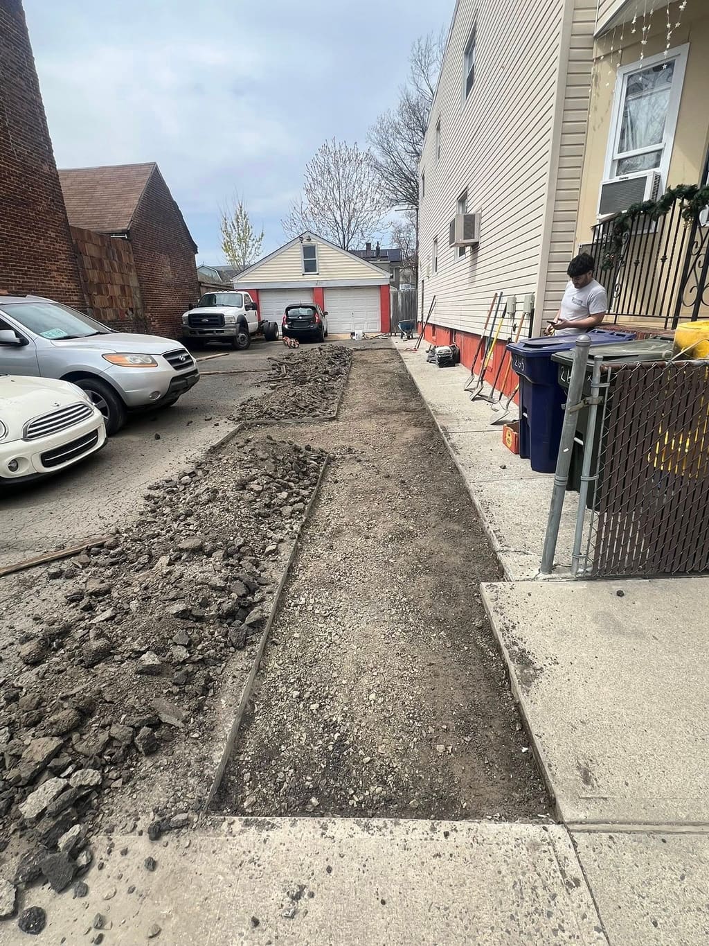 Freshly poured concrete walkway running alongside a house with old concrete demolished nearby.