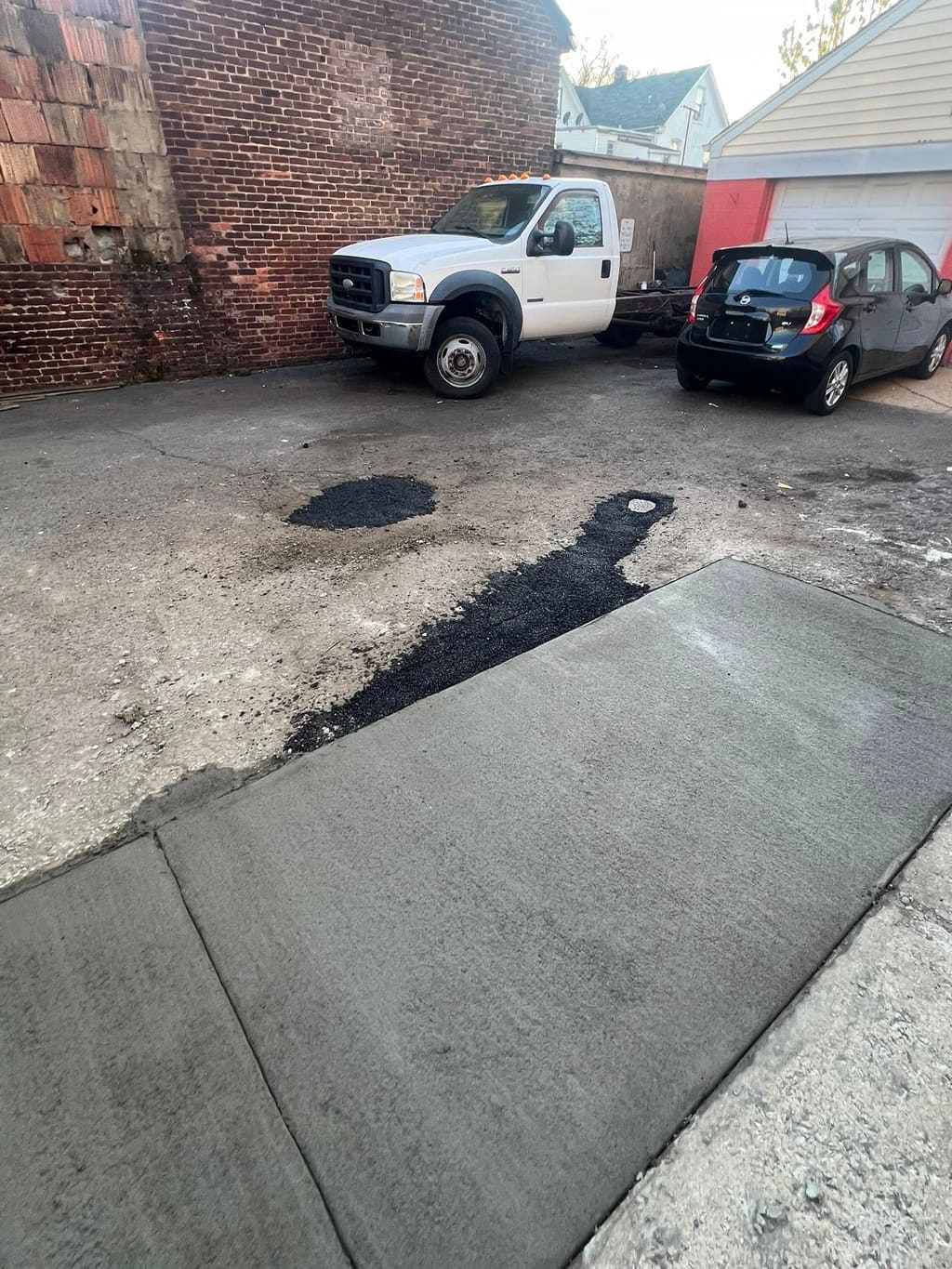Smooth freshly poured concrete driveway apron in a backyard lot with a work truck behind.