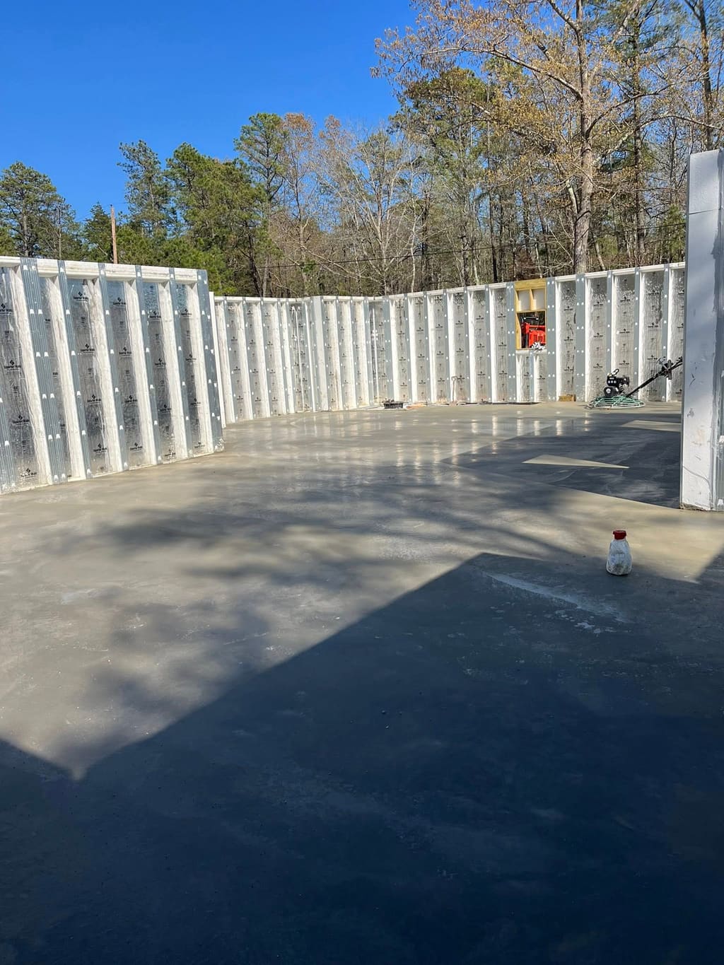 Poured concrete floor slab inside insulated concrete form foundation walls on a wooded lot.