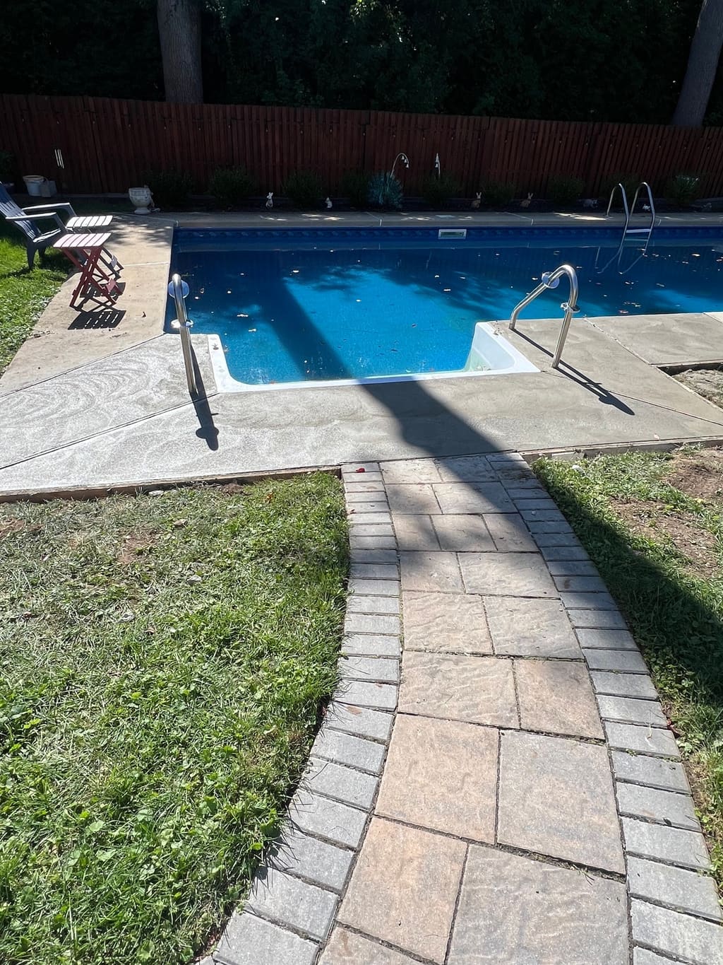 Curved paver walkway with a soldier-course border leading across a lawn to an in-ground pool deck.